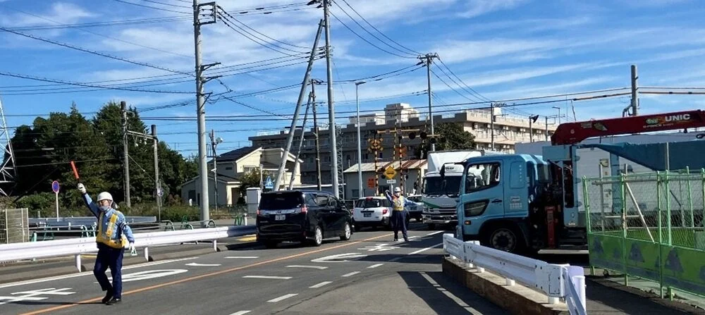 交通整理,警備員,道路,車,トラック,クレーン車,電柱,電線,青空,工事現場,街並み,日中