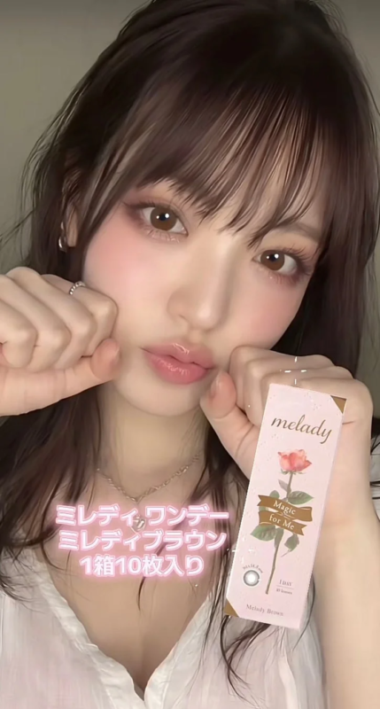 若い女性が「melady」ブランドの「ミレディワンデー ミレディブラウン」カラコンを手に持ち、顔のアップで紹介している
