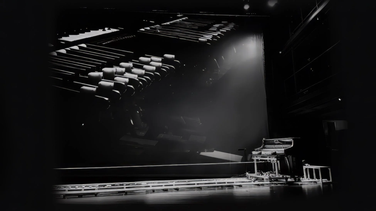 ステージ上のグランドピアノがスポットライトに照らされているモノクロ写真。客席らしき構造が奥に見え、静寂な劇場の雰囲気が漂う。開演前か終演後を思わせる、どこか物憂げな光景。
