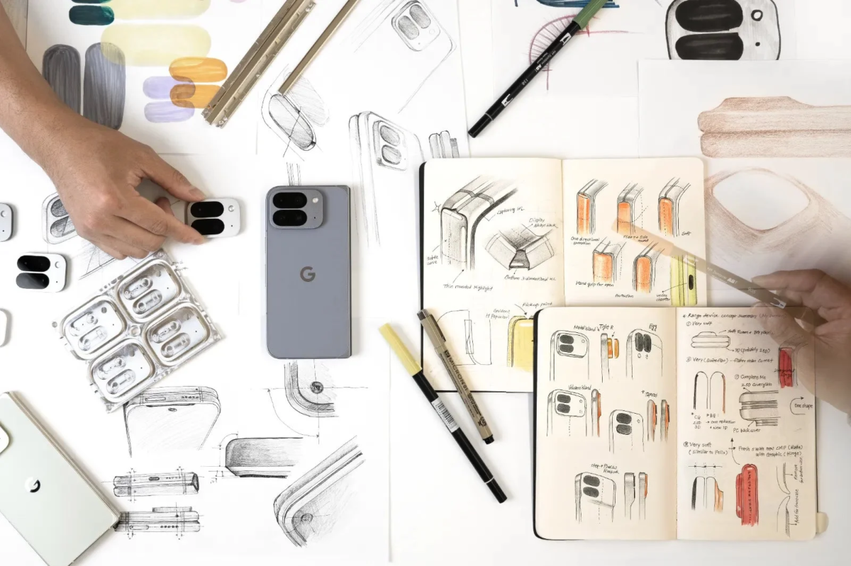 Google Pixelのようなデバイス、取り外し可能なカメラモジュール、そして詳細な手書きの設計スケッチが広がる。デザイナーがプロトタイプを手に取り、製品の形状や機能について検討する、創造的なプロセスの一端が示されている。
