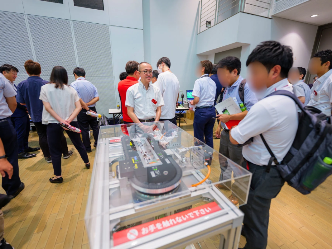 機械の展示物を囲んで説明を聞く人々