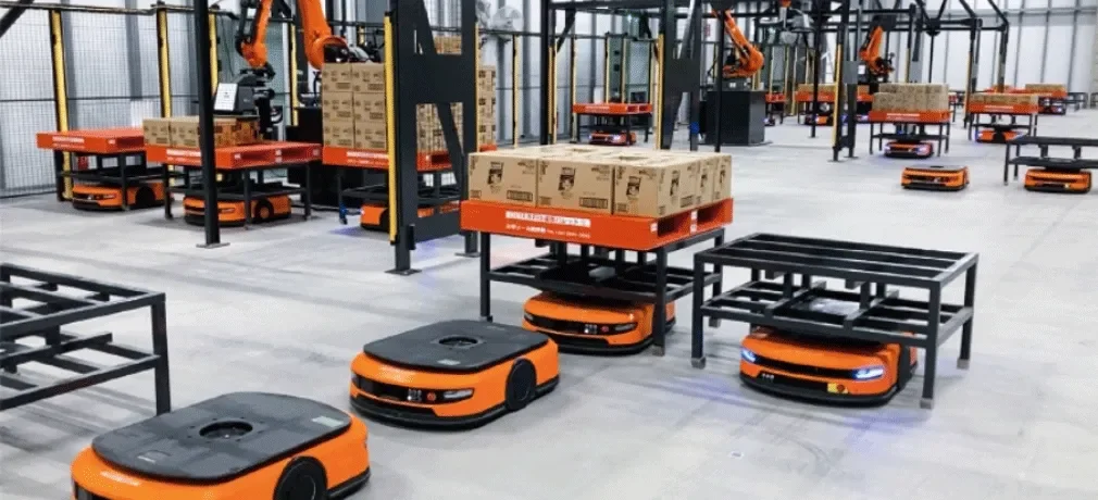自動化された倉庫で段ボール箱を運搬する複数のオレンジ色の自動搬送ロボット