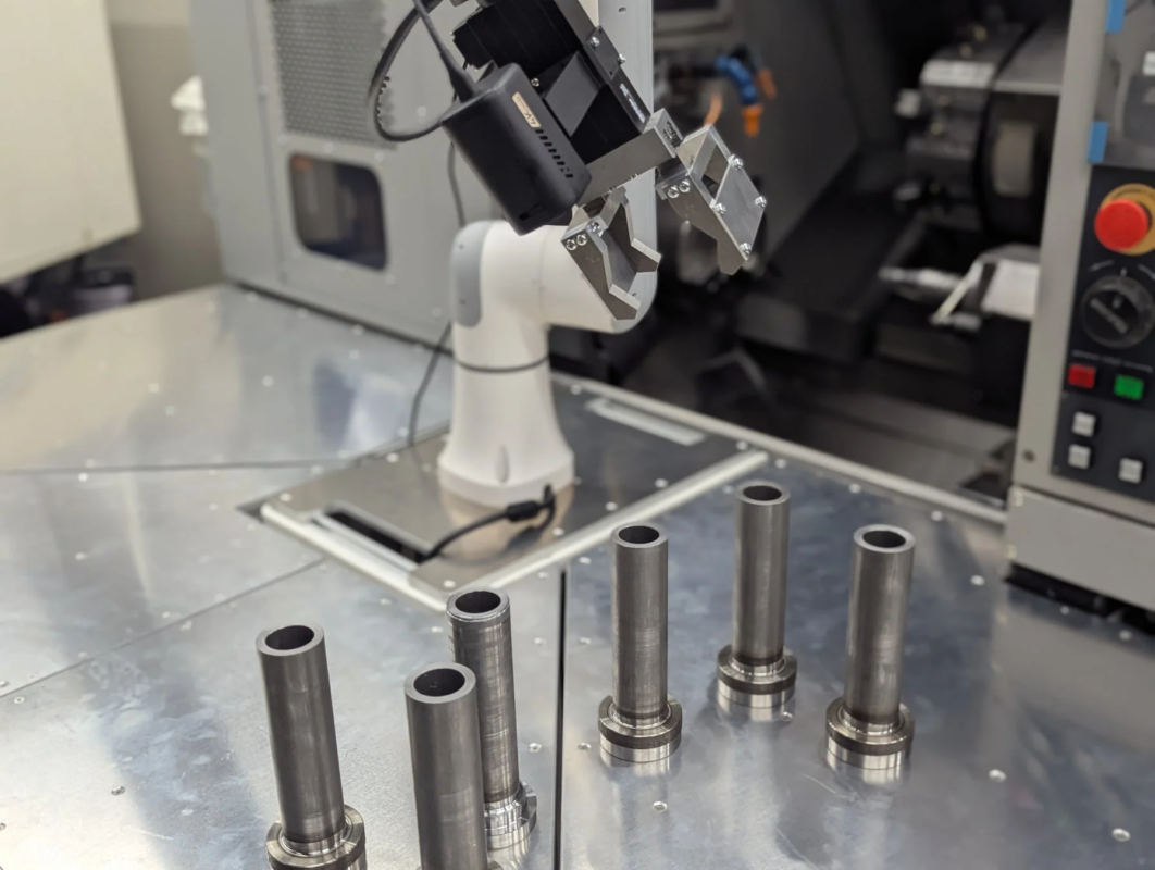 ロボットアームが金属部品の近くに位置しており、産業用オートメーション環境での部品のハンドリングを示唆しています。