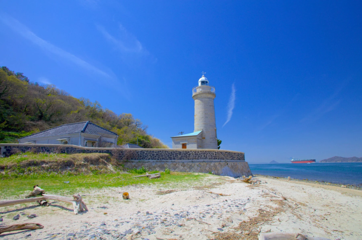 青い空と海が広がる海岸に立つ白い灯台の風景