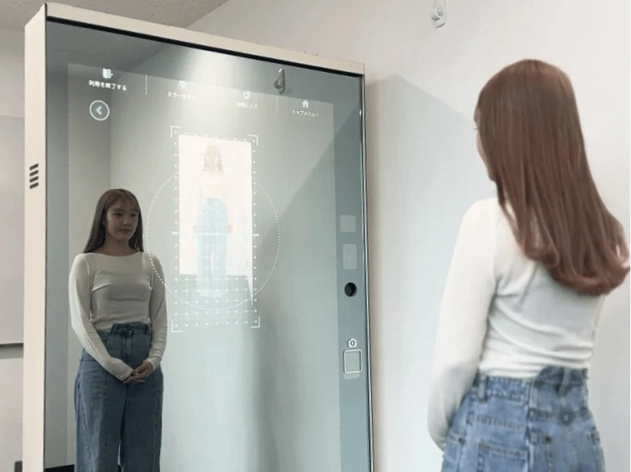 女性がスマートミラーの前に立ち、画面に表示されたバーチャルな自分の姿を見ている