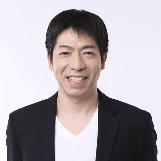 白い背景の前で、黒いジャケットと白いVネックシャツを着用したアジア人男性が、満面の笑みを浮かべているポートレート写真です。親しみやすく、清潔感のある印象を与えます。