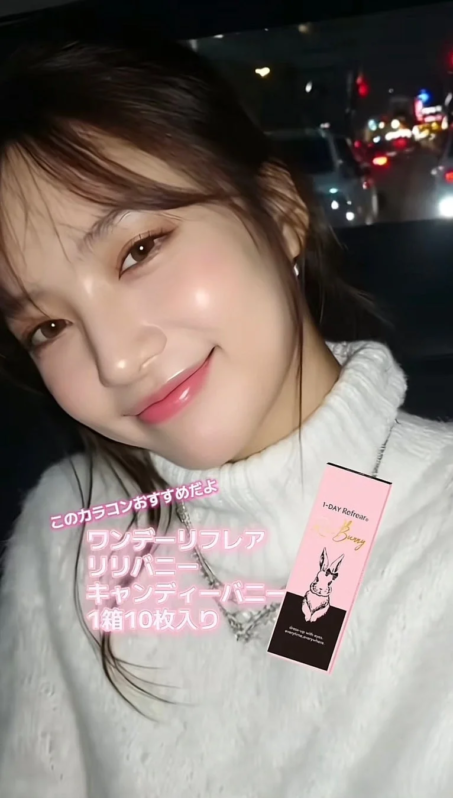 白いセーターを着た若い女性が、笑顔で「1-DAY Refrear LiLi Bunny」のカラコンパッケージを持っている