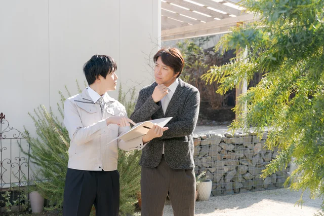 屋外で打ち合わせをする男性二人