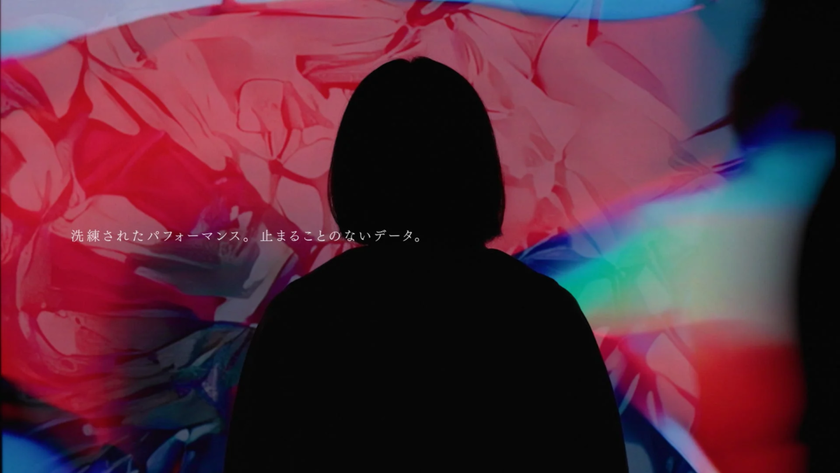 人物のシルエットが、赤や青の抽象的な光の背景に映し出されています。画像には「洗練されたパフォーマンス。止まることのないデータ。」というテキストが表示されており、先進的なテーマを示唆しています。