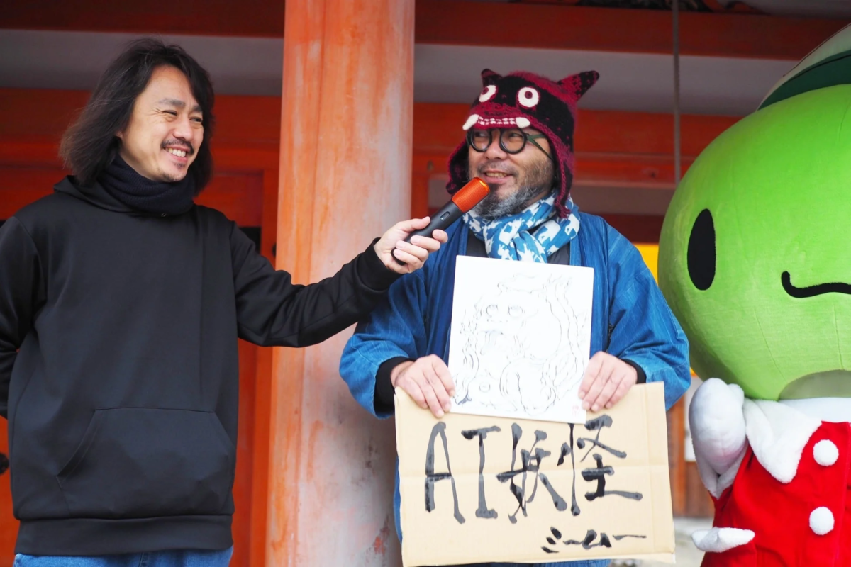 マイクを持つ男性と「AI妖怪」のボードを持つ男性