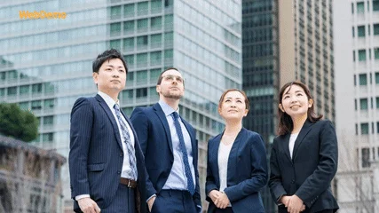 高層ビルを背景に、ビジネススーツを着た4人のプロフェッショナル