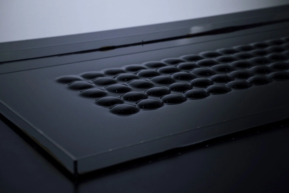 暗い光沢のある表面に、規則的に並んだドーム状の突起が特徴的な画像です。ミニマルでモダンな印象を与え、触覚的なインターフェースや装飾パネルのようです。