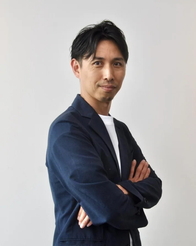 男性が腕を組んで笑顔でカメラを見つめているポートレート写真