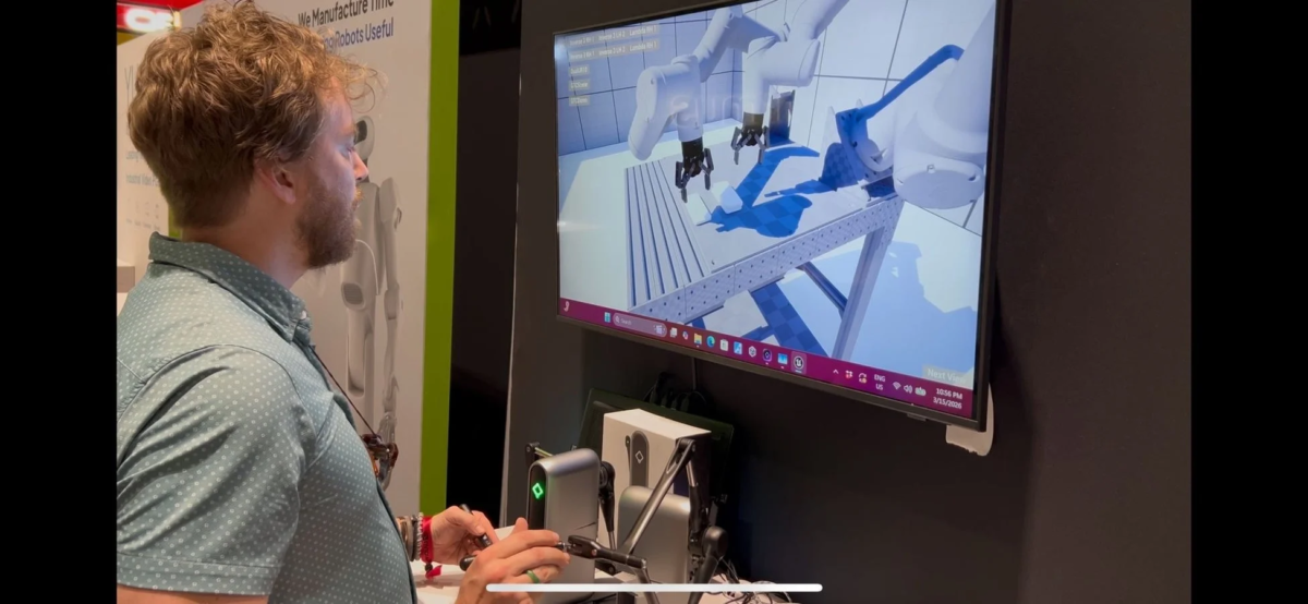 男性がモニターに表示されたロボットアームの3Dシミュレーションを操作している。