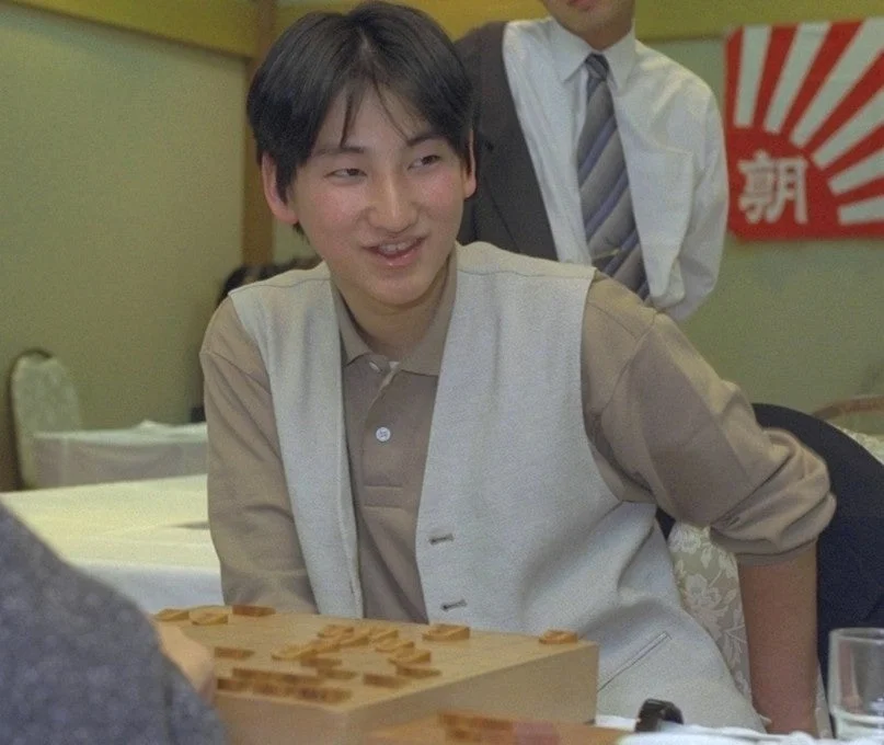 将棋のようなボードゲームを囲んで座る若い人物