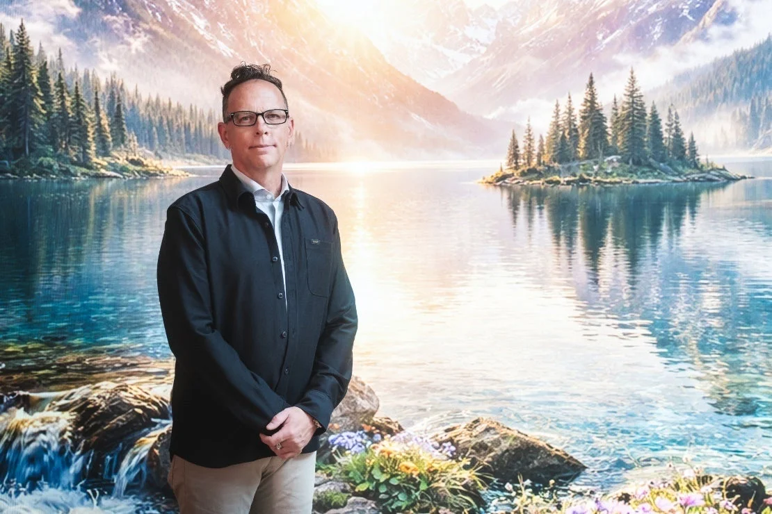 湖と山の風景を背景に男性が立つ