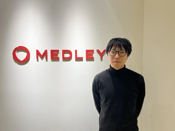 黒いタートルネックを着てメガネをかけた男性