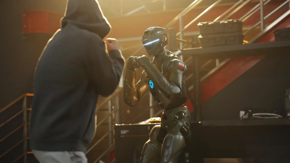 フードをかぶった人物とロボットが向かい合い、ボクシングのような構えで対峙している