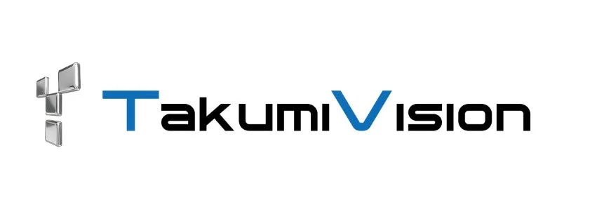 「TakumiVision」という社名またはブランド名を示すロゴ画像です。左側には銀色の立体的な幾何学的なアイコンがあり、右側には「TakumiVision」の文字が書かれています。「T」と「V」の文字は青色で、その他は黒色で表示されており、モダンで技術的な印象を与えます。