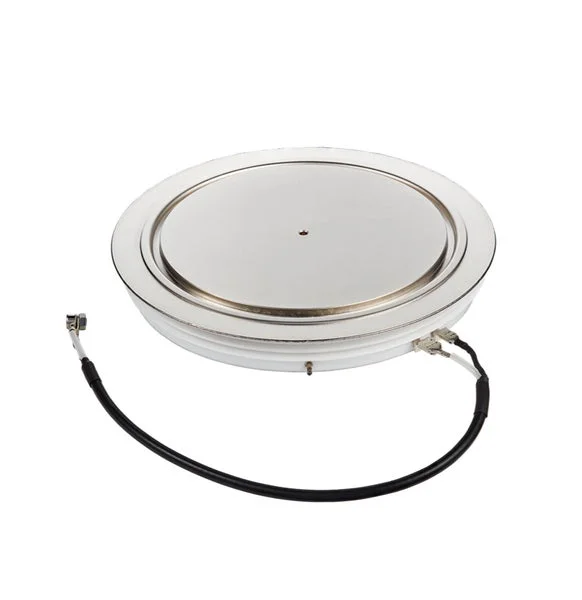 白い背景に置かれた、ディスク型の金属製電子部品です。側面には接続用のケーブルが二本伸びており、高出力用途の半導体デバイス、例えばサイリスタやダイオードである可能性が高いです。