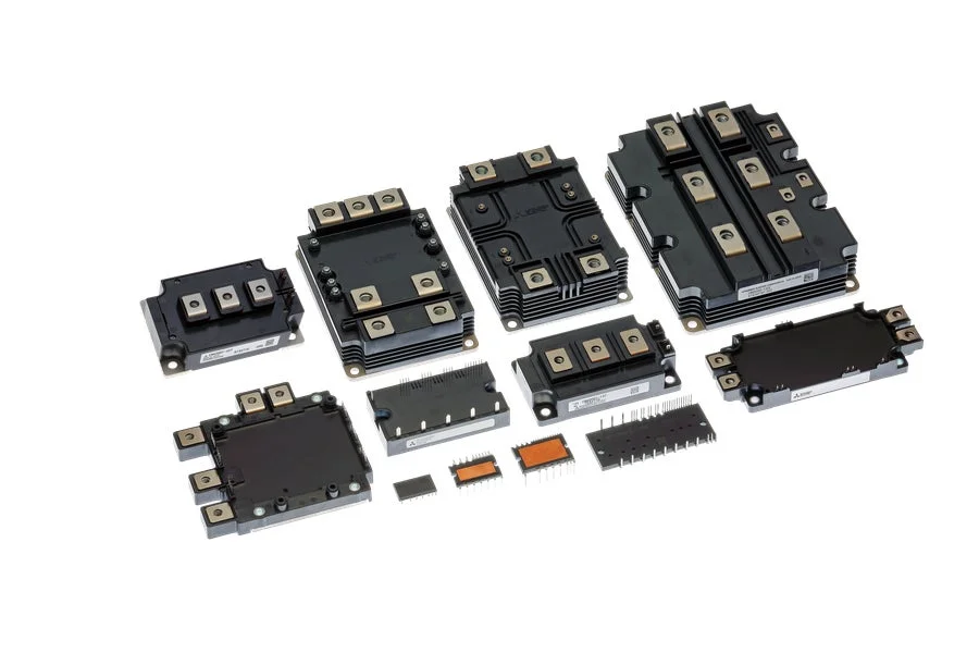 白い背景に様々なサイズの黒い電子部品が並んでいます。これらはパワーモジュールや集積回路などの半導体製品で、産業用電子機器に利用されます。