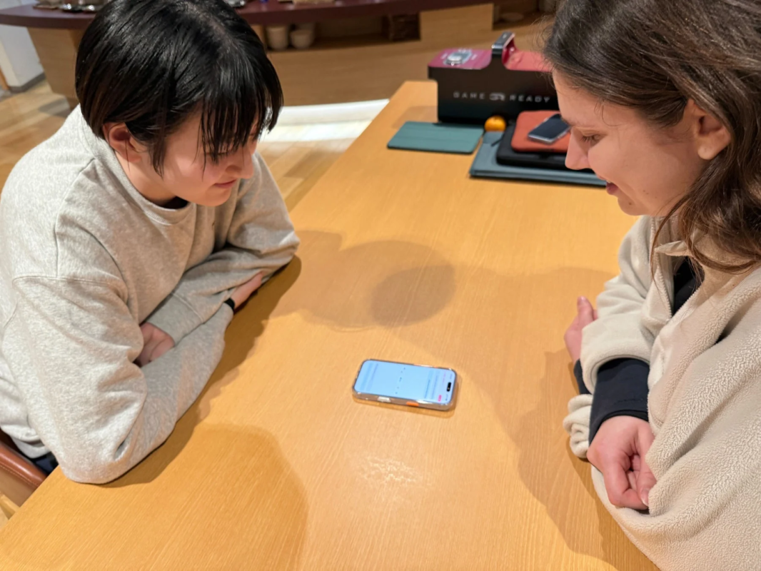 スマートフォンを囲んで会話する女性選手