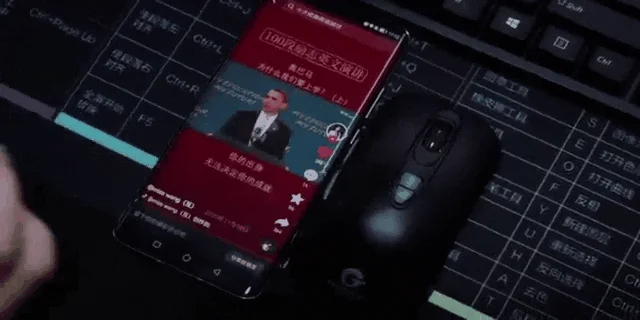 スマートフォンとキーボード、マウスが置かれたデスクで動画を視聴する様子