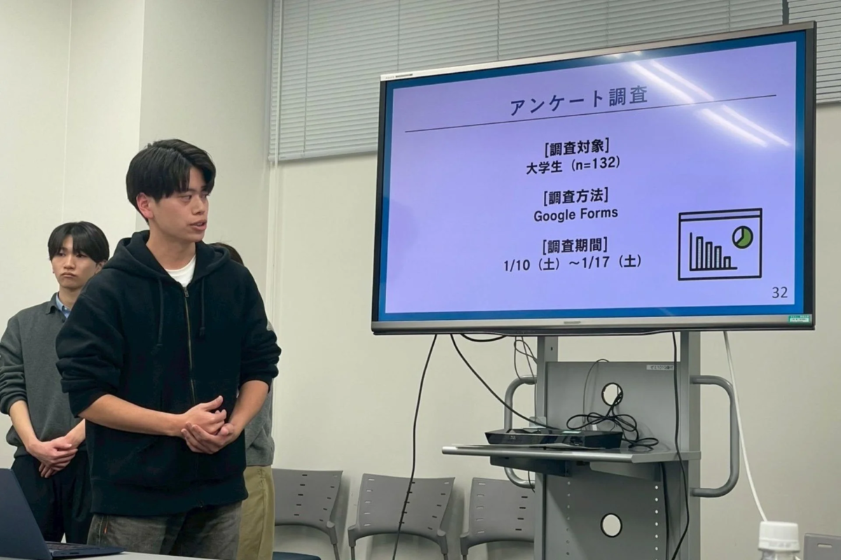 大学の教室で学生がアンケート調査の結果についてプレゼンテーションを行っている様子