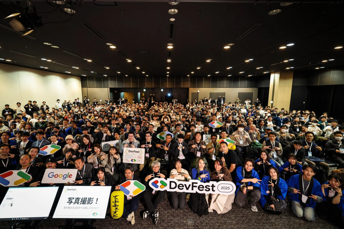 Google DevFest 2025の会場で、多数の開発者や参加者が笑顔でポーズをとる集合写真。